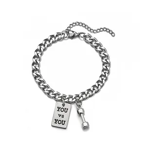 Detail of silver Cuban chain bracelet featuring dumbbell charm and YOU vs YOU plaque
