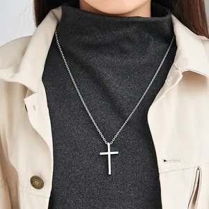 Minimalist silver titanium steel cross pendant necklace worn over a grey turtleneck