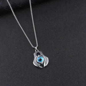 Close-up of punk style evil eye pendant with blue pupil texture on metal chain