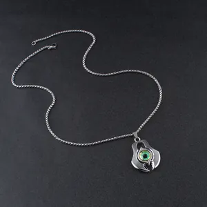 Detailed view of punk devil eye pendant with green pupil and silver box chain