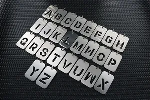 Makroansicht von 26 Anhängern aus gebürstetem Edelstahl mit hohlen Buchstabenausschnitten