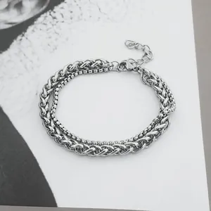 Detail eines silbernen doppellagigen Kettenarmbands mit Karabiner auf minimalistischem Grund