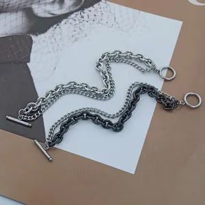 Detail of layered stainless steel OT buckle chain bracelet in black and silver metallic tones