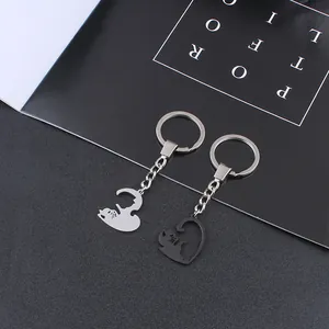 Close-up of stainless steel couple cat keychains forming a heart shape with a matte finish