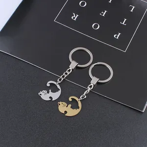 Detail view of interlocking gold and silver stainless steel cat couple keychains on table