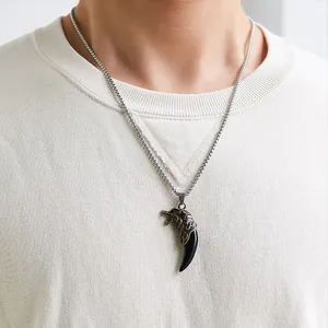 Detail of a vintage wolf tooth pendant on a beaded chain necklace for men in casual wear