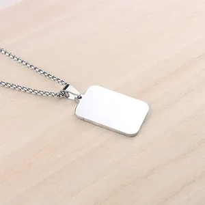 Close-up of polished silver rectangular pendant with box chain on wood background