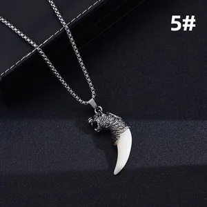 Detailed macro view of a vintage silver tiger head pendant with a curved white tooth charm