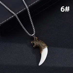 Detail of vintage bronze tiger head pendant with white tusk on steel pearl chain