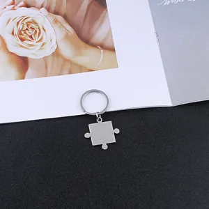Detailopname van zilveren roestvrijstalen puzzelvormige sleutelhanger op contrastbasis