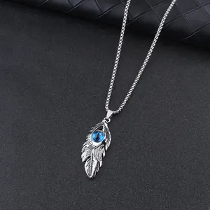 Detailed close-up of retro feather wing necklace with blue evil eye pendant on textured base