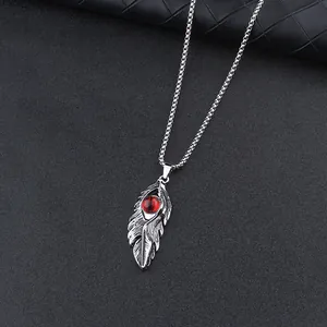 Detailed close-up of gothic feather pendant with a red devil eye on a pearl chain