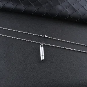 Dettaglio del ciondolo a proiettile in argento lucido con catena in metallo sottile