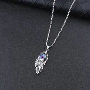 Macro shot of silver feather pendant with blue evil eye detail on a box chain