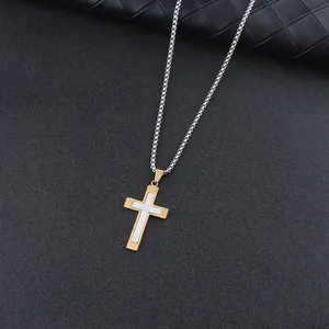 Detail of two-tone steel cross pendant on silver box chain over quilted leather backdrop
