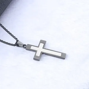 Macro detail of a two-tone black and silver steel cross pendant on a dark chain link