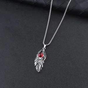Vintage silver feather pendant necklace with a bold red dragon eye stone on black background