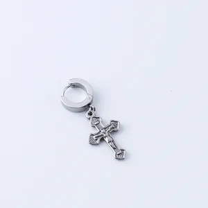 Macro detail of stainless steel cross earring with religious relief on huggie hoop