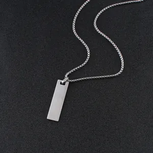 Detail shot of a silver rectangle pendant on a sturdy box chain over a textured grey surface
