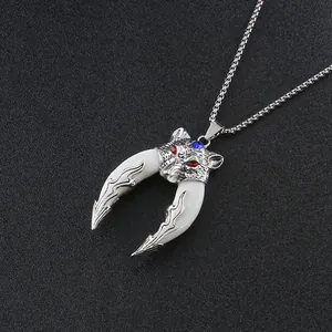 Detailed close-up of a silver wolf head pendant with two white tusks and red gemstone eyes