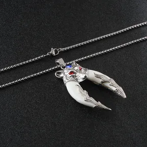 Detailed view of silver wolf head pendant with red and blue gem eyes and dual white tusks