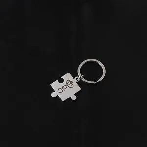 Detailed close-up of king and queen crown puzzle keychain in brushed stainless steel