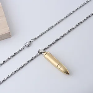 Detalle de un colgante de bala dorada con una cadena box plateada en fondo blanco