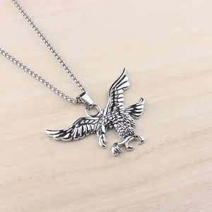 Dettaglio del ciondolo aquila argento con piume rifinite su sfondo in legno naturale