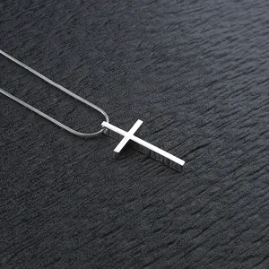 Collana con ciondolo a croce in acciaio lucido e catena a serpente su pelle scura
