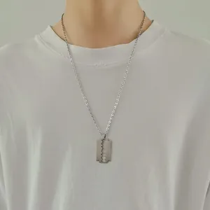 Polished silver stainless steel razor blade pendant necklace on a plain white T-shirt