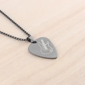 Detailed macro view of a dark grey brushed stainless steel guitar pick pendant and chain
