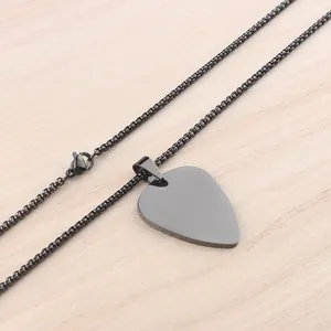 Black stainless steel guitar pick necklace with a matte finish on a wooden background
