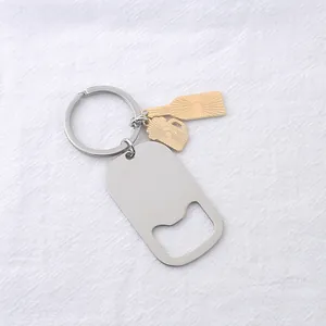 Détail d'un porte-clés décapsuleur en acier avec breloques dorées sur tissu de lin blanc