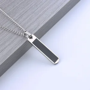 Minimalist stainless steel bar necklace with black inlay on a geometric wood stand