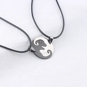Close-up of cat-shaped yin yang puzzle pendants in black and silver on white fabric