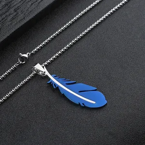 Detailed close-up of blue feather pendant with silver box chain on dark textured surface
