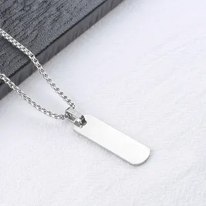 Primer plano de un colgante rectangular plateado y cadena de caja para hombre sobre blanco