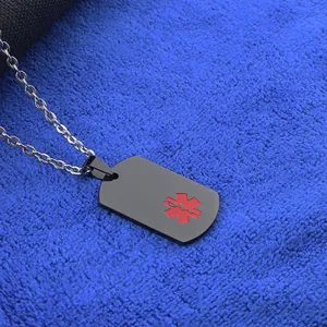 Détail d'un pendentif d'alerte médicale noir avec symbole de vie rouge sur une chaîne en acier