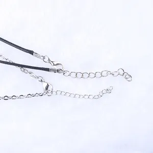 Dettaglio macro della chiusura a moschettone argento e catenina su collana in corda