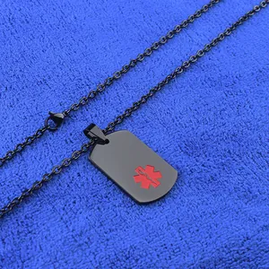 Détail d'un pendentif médical rectangulaire noir avec symbole d'alerte rouge sur tissu bleu