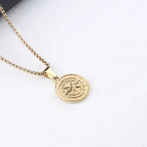 Detailed macro view of a gold compass coin pendant with an engraved box chain necklace