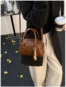Sac baguette vintage marron avec breloque perlée sur fond de rue automnale
