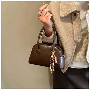 Détail du sac en cuir marron avec logo Sims Cat gaufré et pendentif en perles de bois