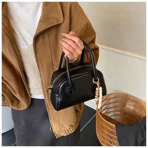 Détail du sac baguette vintage en cuir noir avec breloque perlée et finitions dorées