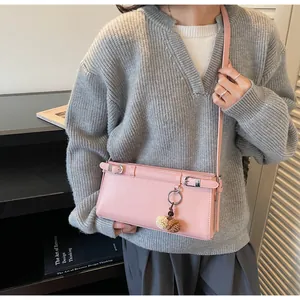 Détail du sac baguette en similicuir rose avec boucles argentées et breloque en peluche douce