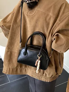 Sac Boston noir vintage avec doubles poignées et breloque perlée porté par mannequin