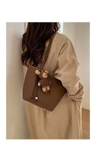 Detailed view of dark brown pebbled leather tote bag with a cute plush bear charm