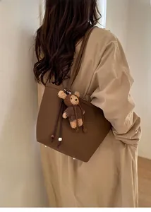 Rear view of model wearing a dark brown lychee leather tote bag with a cute bear charm