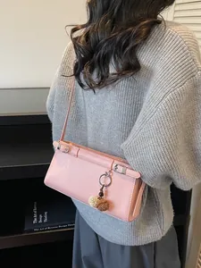 Sac baguette chic en cuir PU rose avec sangles décoratives et pendentif pompon doux