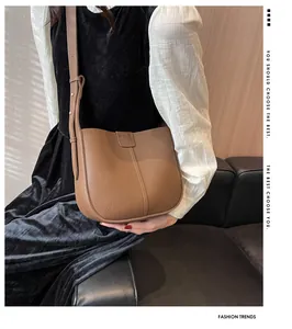 Gros plan du sac seau en cuir marron à texture litchi avec bandoulière réglable
